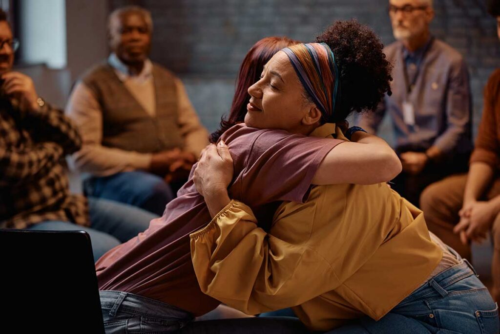 Supportive women embracing during group therapy